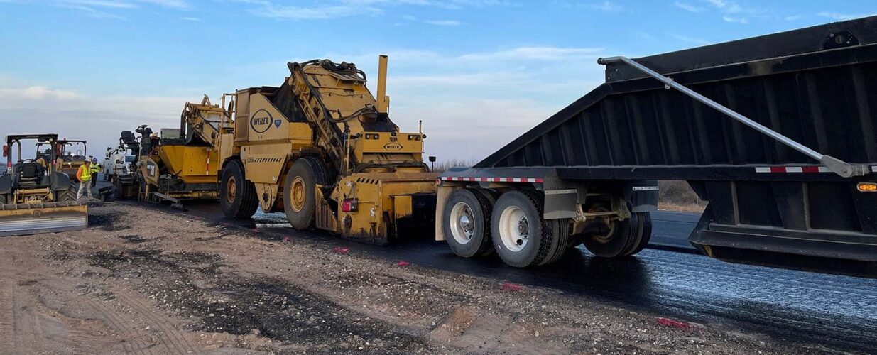 paving trucks at SH 302 for widening and improvements